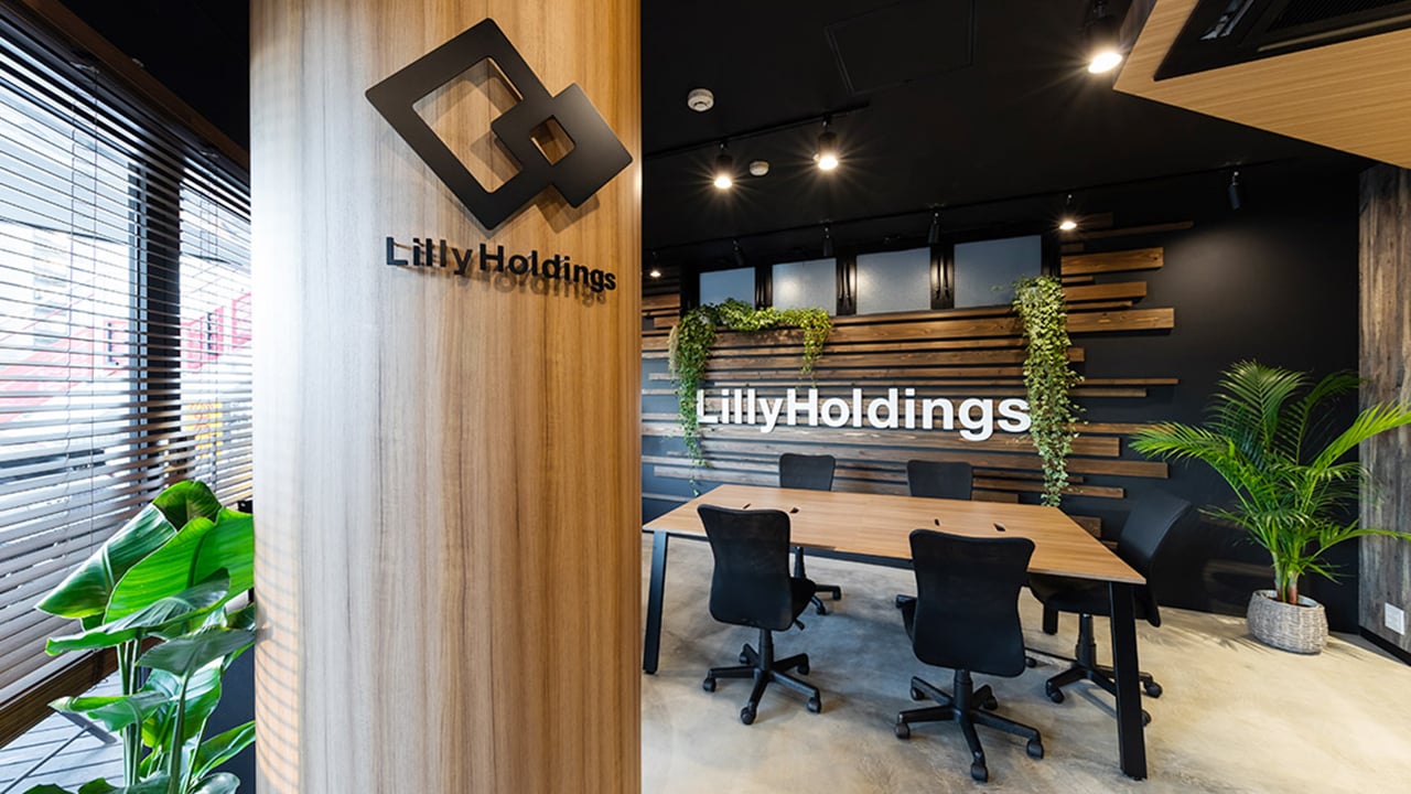 株式会社LillyHoldings様のオフィス内観。木目調の壁と観葉植物を取り入れたミーティングスペース