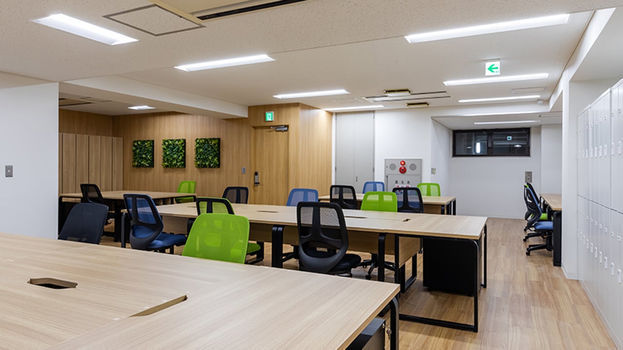 株式会社ネットレイズ様の木目調デスクとグリーンのチェアを取り入れた執務スペース