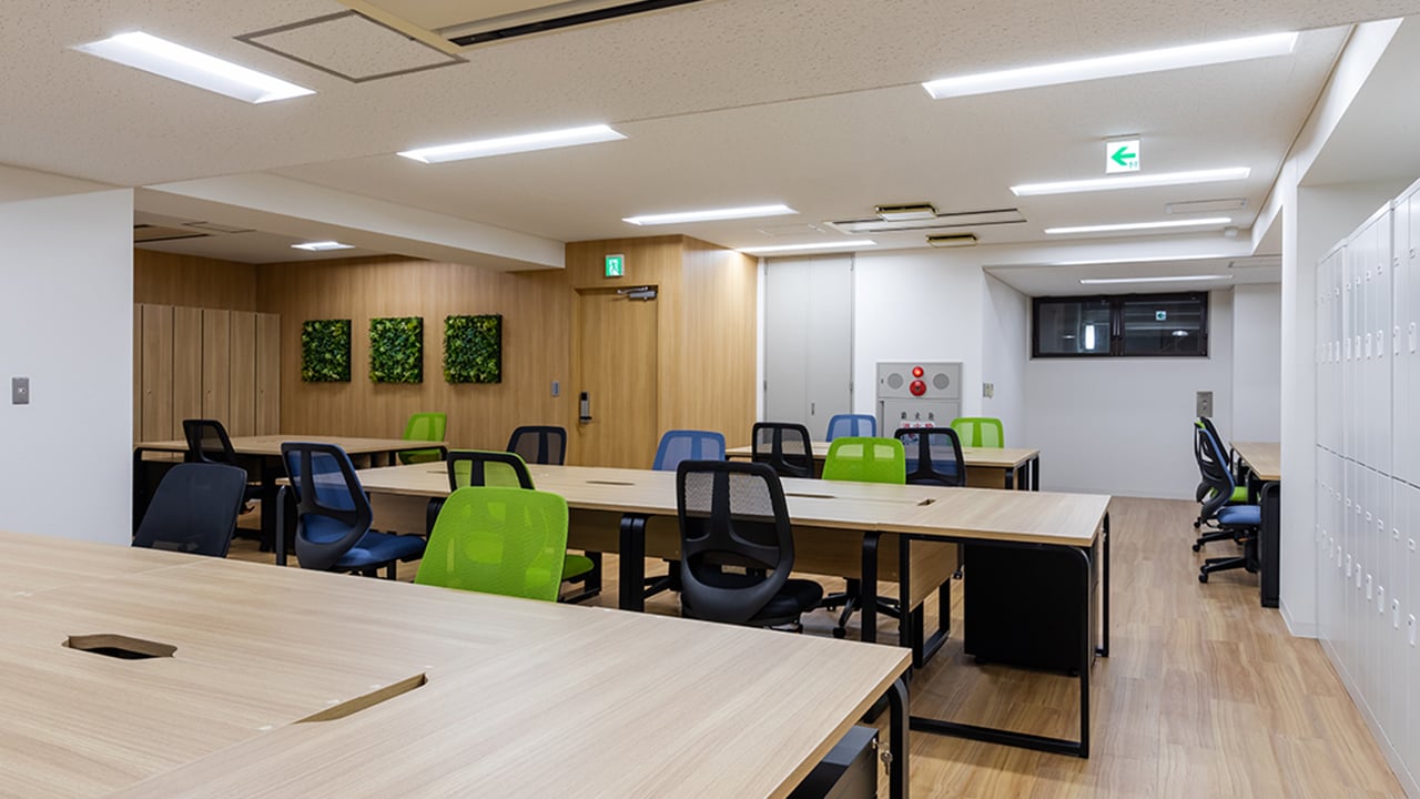 株式会社ネットレイズ様の執務スペース。木目調デスクとグリーンの家具を取り入れたオフィス
