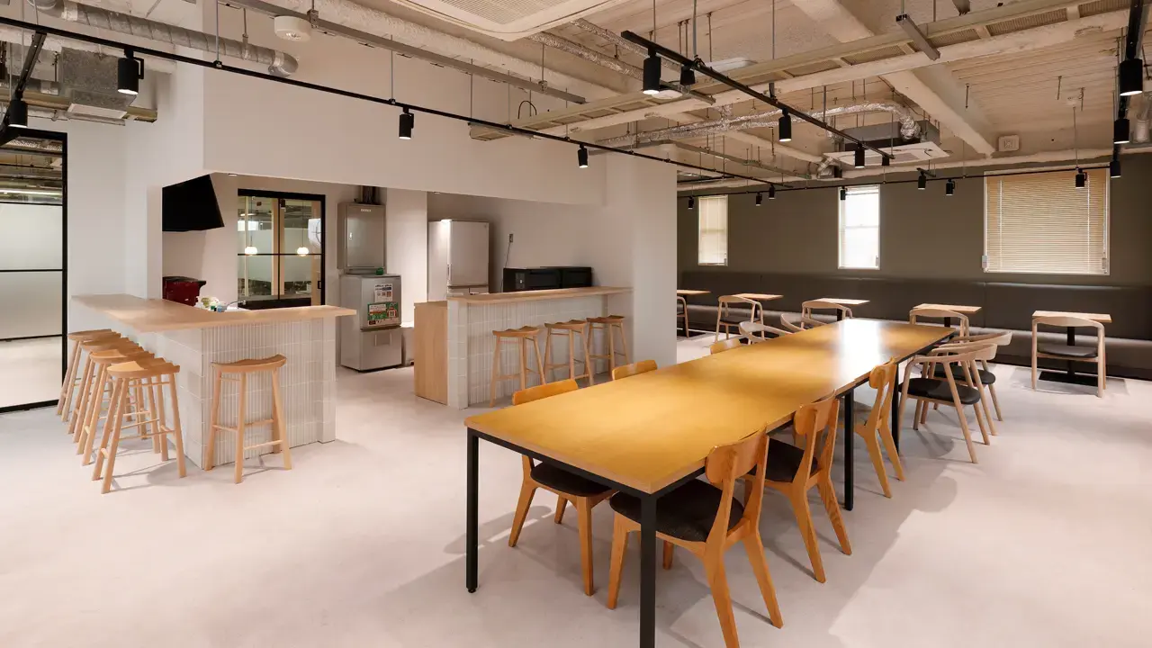 約120坪のカフェ風オフィス事例。木製カウンターと長テーブルを組み合わせたオープンな休憩エリア