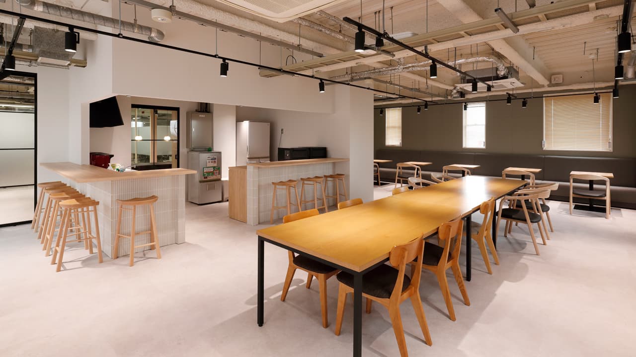 約120坪のカフェ風オフィス事例。木製カウンターと長テーブルを組み合わせたオープンな休憩エリア