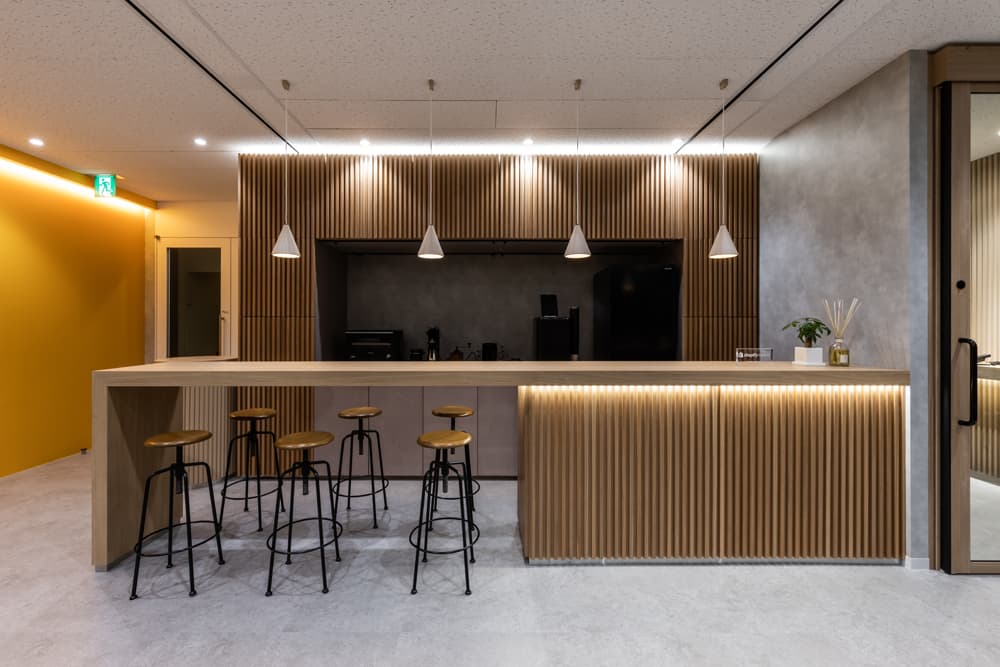 約82坪のカフェ風オフィス事例。木目のカウンターとハイチェアを設置した交流促進スペース